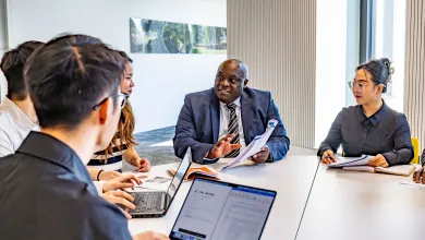 Professor Ven Tauringana and students dicussing at table
