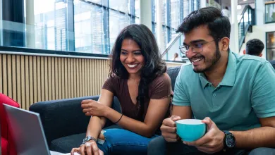 Two students huddle around a laptop together checking information on the screen.
