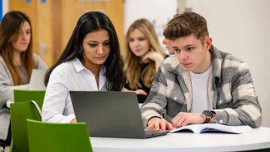 Two students at a table with a laptop