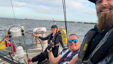 Participants on a sailing session out on the water smiling taking a selfie
