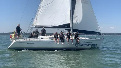 Crew sitting on the side of a yacht sailing on the sea.