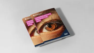 A small stack of university prospectuses on a table. The front cover of the prospectus reads 'Undergraduate Prospectus 2026' and features a close-up image of an eye, with the reflection of an open book.