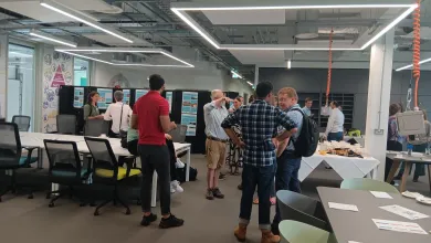 Modern office space with several people engaged in conversation around a table filled with refreshments. 