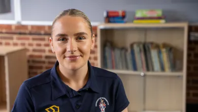 Head and shoulders portrait image of Alice wood wearing a navy blue tee shirt with a University PGCE PE logo.