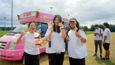 Three students stood holding ice creams, with an ice cream van in the background.