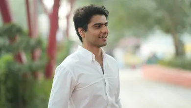 Law graduate and entrepreneur Rohit is standing looking to the right of the camera. There are out of focus trees and shrubs behind him.