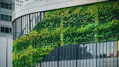 A modern building in an urban environment covered with glass panels and greenery.
