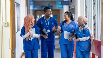 A group of 4 medical students wearing blue scrubs Group of 4 medical students wearing blue scrubs, walking and talking in a hospital corridor