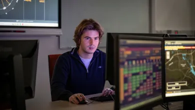 Stefan using a computer in a classroom for his finance and economics degree. 