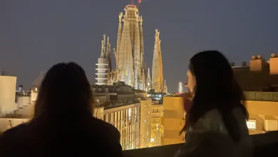 Two students on a balcony looking out at Barcelona cathedral lit up in the night sky.