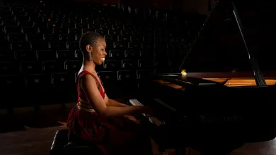 Dr Samantha Ege performing at a grand piano in a concert hall.
