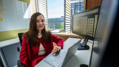 Dr Larisa Yarovaya working at her desk with laptop and monitors in an office.