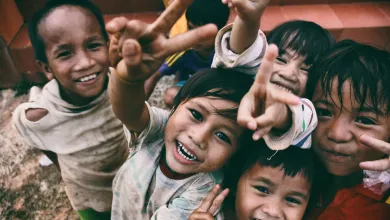 A group of children smiling at the camera outside.