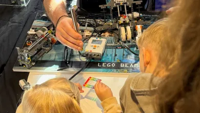 Children take part in a hands-on electronics activity using a LEGO-based machine and sensor equipment at a science demonstration.