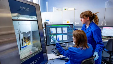 A senior researcher mentors a junior researcher in the use of a system