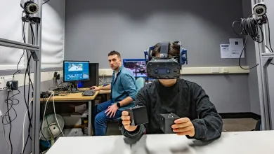 Researchers sitting down at a computer and one with a visor on