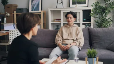 Two people sitting opposite each other talking in a therapy session. 