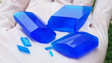 Three large blue crystals surrounded by smaller blue crystals in a white gloved hand