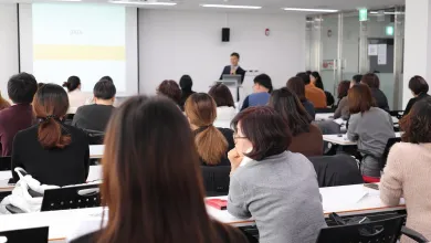 A lecturer stands in front of a classroom of students