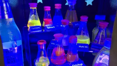 A stand with bottles of various household liquids, all glowing under ultraviolet light