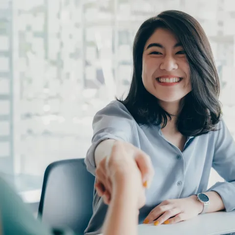 Women shaking hands over a desk