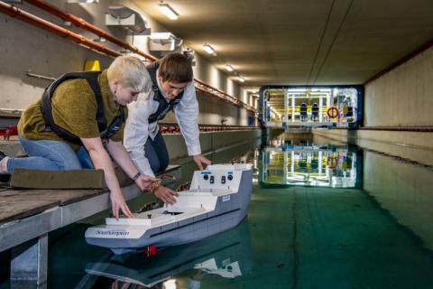 Two students test a model boat in the towing tank