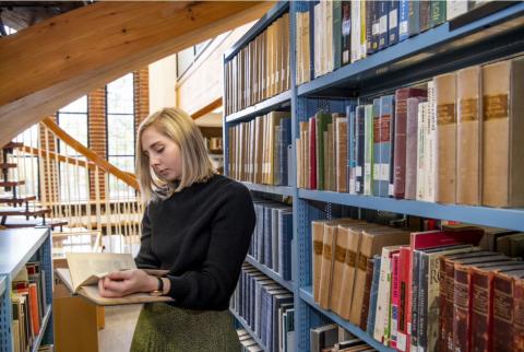 A student browsing by a bookshelf in Hartley Library