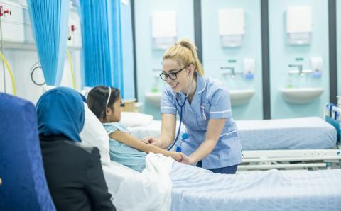 Nursing student tends to child patient at their bedside