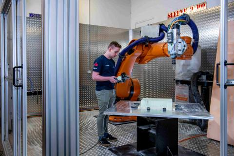 A student uses the robot arm in the engineering design and manufacturing centre