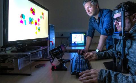 A psychology researcher observes a particpant in an eye tracking experiment
