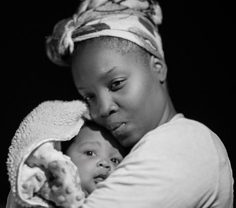 Black and white image of a mother holding her young baby close.