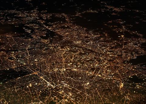 Satellite image of a city showing nighttime activity highlighted by the lights along transport corridors and at points in the city