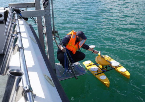 A Southampton Geospatial researcher on a boat prepares a device for collecting data in Studland Bay