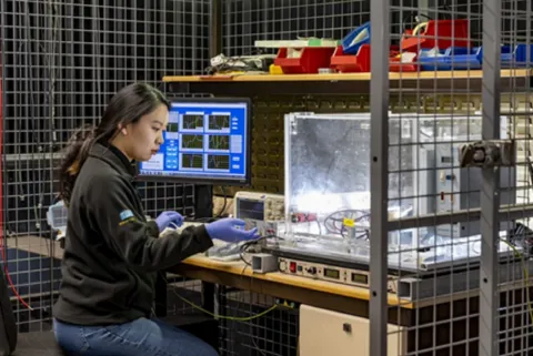 Researcher sitting at a work bench changing equipment settings