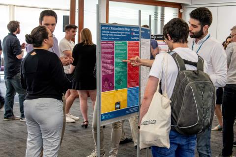 Researchers discussing an academic poster at an event