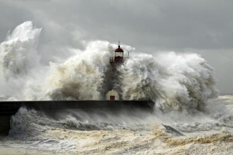 Large waves crash against a lighthouse during a storm surge, an unusual rise in sealevel