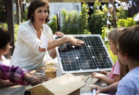 A female teacher showing her pupils a solar panel