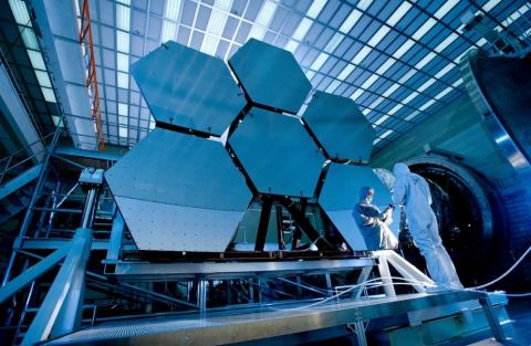 A technician testing hexagonal solar panels for a satellite