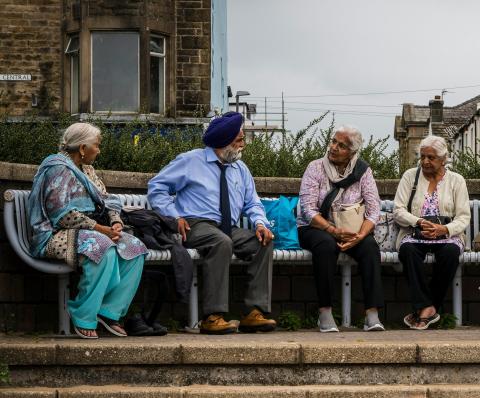 4 people from the Bangladeshi and Pakistani communities sitting on a bench talking