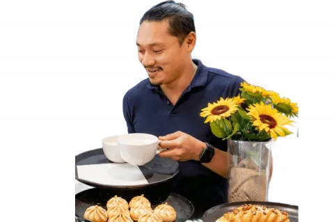 Catering manager Fritz Apellido smiles as he puts coffees on a tray