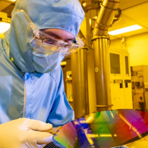A researcher in a cleanroom suit with a 200mm wafer in the nanofabrication cleanroom