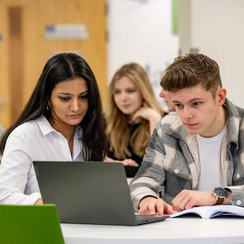 Two students at a table with a laptop
