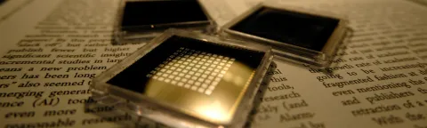 three small square microchips placed on the pages of a book with visible text.