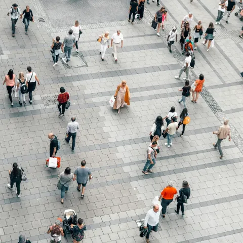 An aerial view of crowds of people walking in an urban environment.
