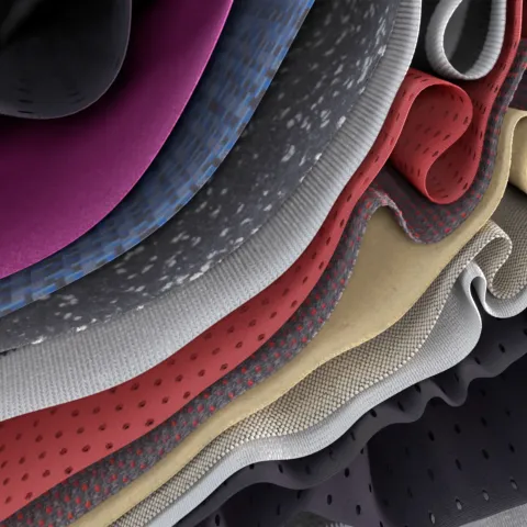 A close-up view of layered, folded fabrics in different colours and textures, shown in a wavy, rippled arrangement.