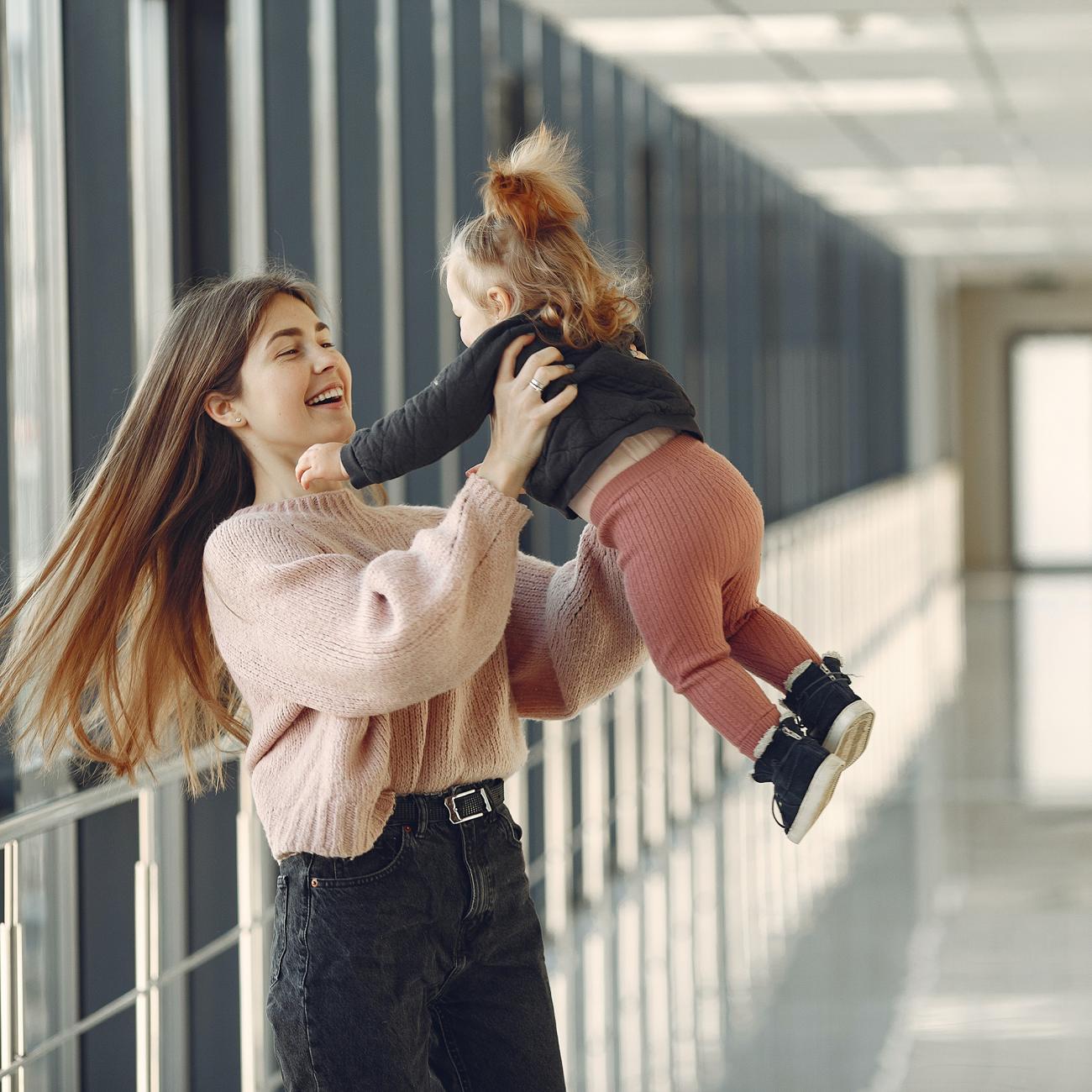 Young student spinning her daughter in a corridor. 