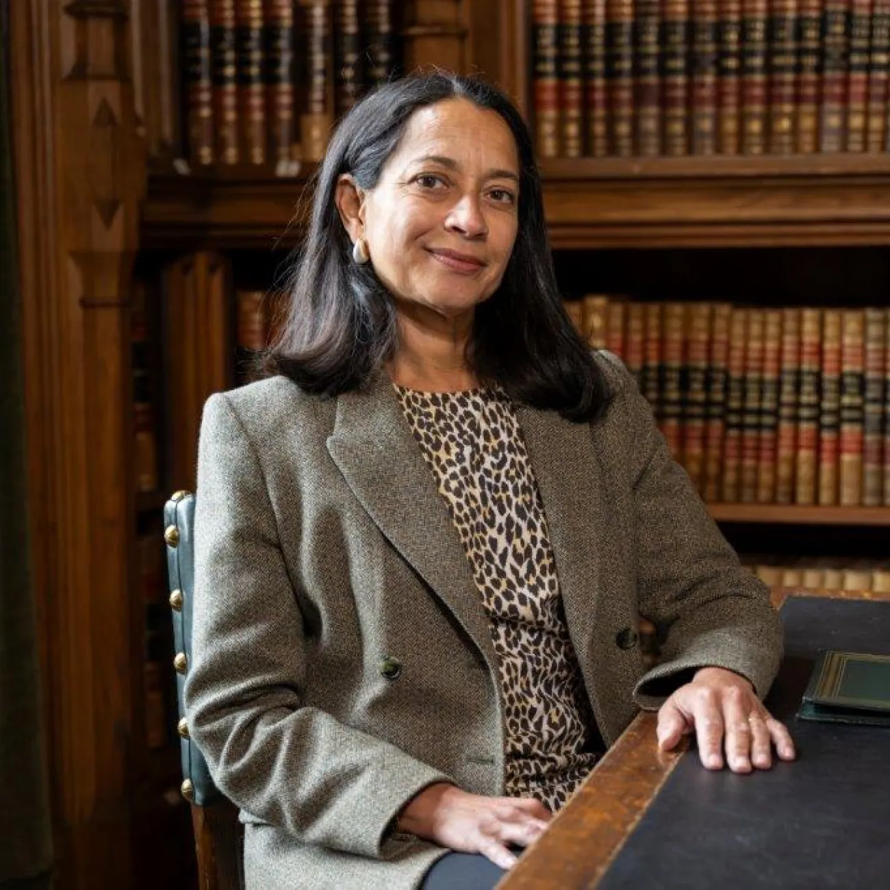 Anna Dickson sat in the House of Commons Library. She's sat at a desk with a bookshelf directly behind her.