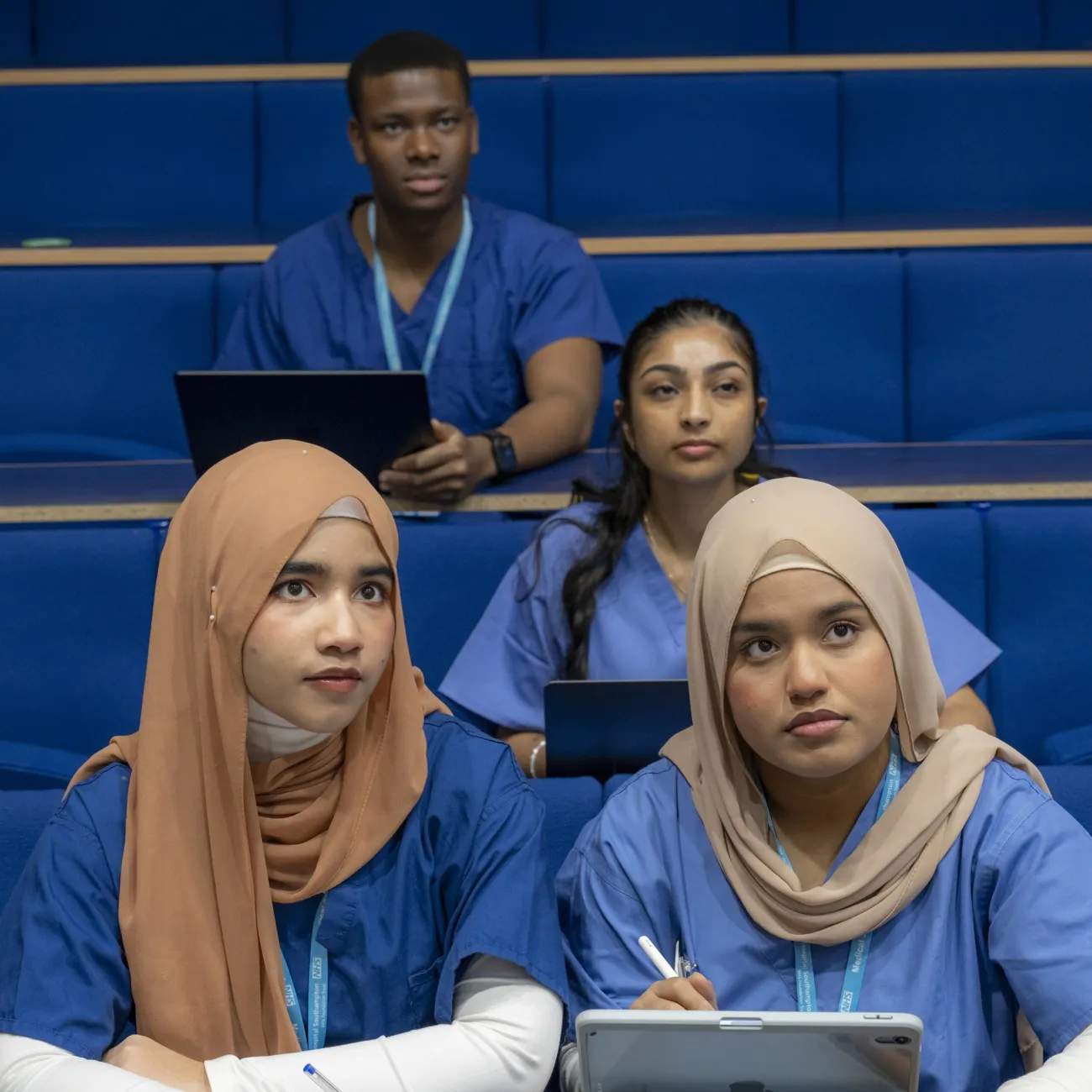A group of 4 medical students sitting in a lecture theatre.
