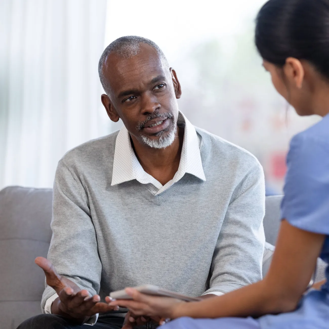 A patient speaking to a doctor in a hospital waiting room.