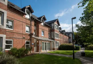 Exterior view of red brick, two storey accommodation building on a sunny day.